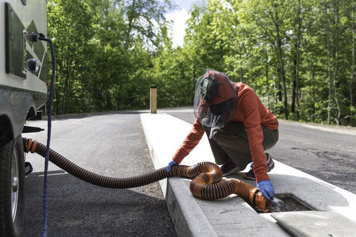 Woman Emptying RV Sewer After Camping debouchage-canalisation
